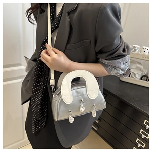 Detail of silver shell bag with white wide handle and pearl pendants on grey blazer