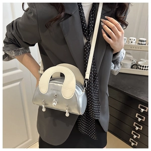 Close-up of silver shell bag with white handle and hanging silver pearl charms