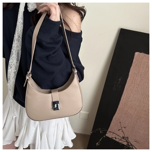 Detail einer beigen Halbmond-Hobo-Tasche mit Silberschnalle und weißem Spitzenband