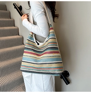 Detail of colorful woven tote bag with wide straps worn by model on stairs