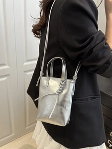 Chic silver metallic bucket handbag with slender straps for modern fashion styling