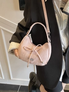 Sac hobo croissant rose avec texture plissée et nœud porté par un mannequin