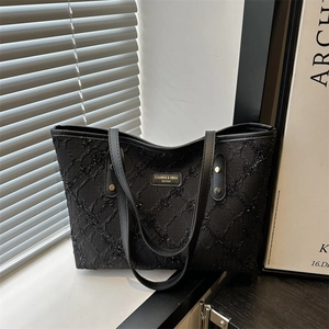 Minimalist black textured tote bag with leather handles and metallic rivet details