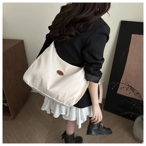 Detail of off-white nylon crescent crossbody bag with fashion leather patch shown on model