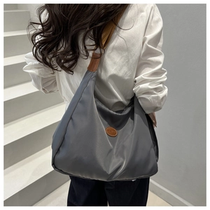 Macro view of dark grey nylon tote bag showing soft pleats and leather handle details