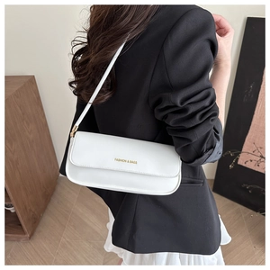 White leather baguette shoulder bag with gold text detail worn by model in suit