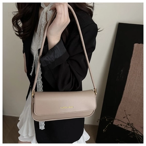 Detail of beige shoulder bag with gold 'FASHION & BAGS' text on matte leather finish