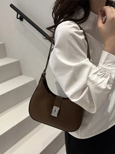 Braune Hobo-Tasche mit silberner Schnalle, getragen von einem Model in minimalistischem Stil