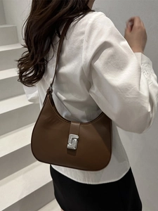 Dunkelbraune Halbmond-Tasche mit silberner Metallschnalle auf schlichtem grauem Hintergrund