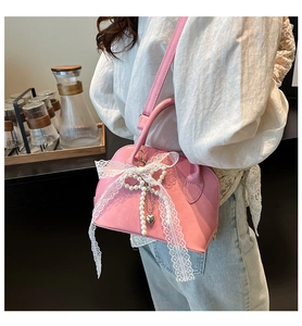 Close-up of pink shell bag with white lace bow, pearl chain and heart pendant detail