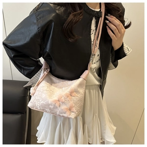 Détail du sac bandoulière en dentelle rose avec applique de papillon 3D brodée