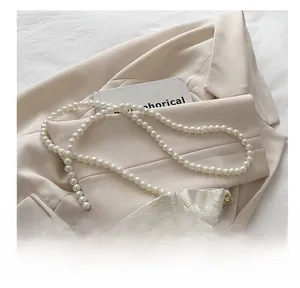 Dettaglio della borsa a secchiello con tessuto jacquard, farfalla 3D e tracolla di perle