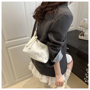 Détail d'un sac à main en dentelle blanche avec motifs floraux et cordon de serrage perlé