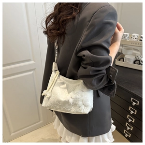 Détail du sac à main en dentelle blanche avec broderies florales et perles élégantes