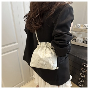 Detail of white lace bucket bag with 3D floral embroidery and a pearl chain strap