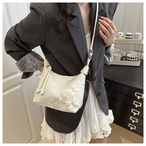 Détail du sac bandoulière en dentelle blanche avec texture fleurie 3D et perles élégantes