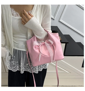 Detailed close-up of a pink patent leather handbag with a white lace bow and gold hardware