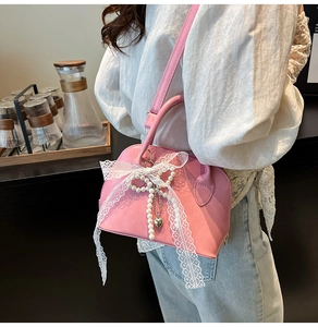 Pink lace shell bag with pearl heart charms and bow detail shown in lifestyle use