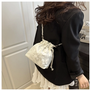 Detail of ivory lace bucket bag with 3D butterfly appliques and long pearl strap