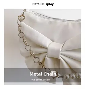 Details der weißen Handtasche mit goldener Kleekette und eleganten Perlenakzenten