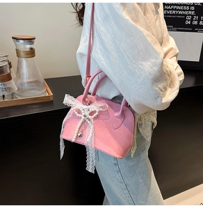 Pink shell bag with large lace pearl bow and heart pendant worn by model in a cafe