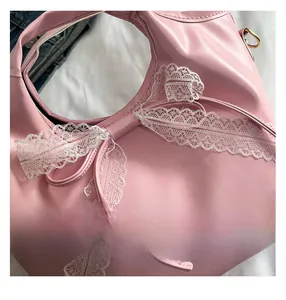 Detail of pink faux leather bag featuring elegant white lace bow decoration
