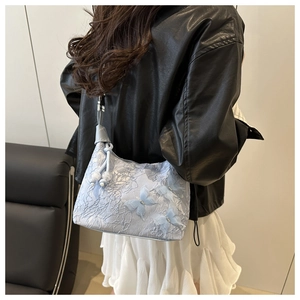 Détail du sac à bandoulière en dentelle bleu clair avec papillon en soie 3D sur un modèle