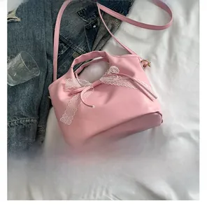 Detail of pink PU leather handbag with white lace bow decoration and slim shoulder strap