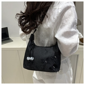 Détail du sac bandoulière en satin noir avec broderie florale et pendentif perlé