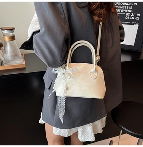 Detail of cream lace bow and pearl pendant on stylish faux leather crossbody shell bag