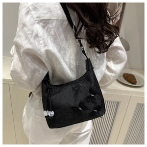 Détail du sac à bandoulière noir de style chinois avec broderies florales et breloques papillon