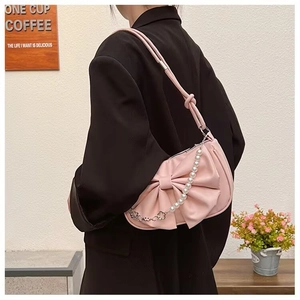 Rosa Schleifen-Schultertasche mit Perlen- und Metallblumenkette am Model getragen