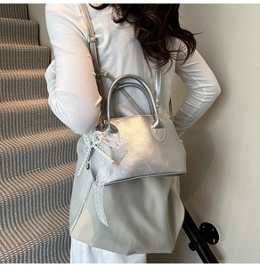 Detail of silver shell bag with delicate lace bow and pearl pendant on a shoulder strap