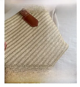 Close-up of beige woven tote bag with detailed wavy straw texture and brown leather loops
