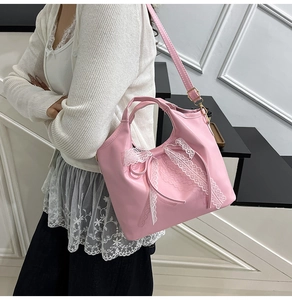 Detail of pink bag with white lace and bow being worn by a model in a minimal setting