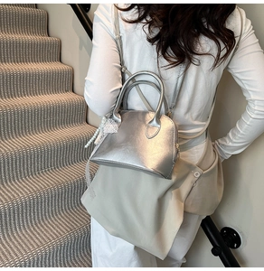 Silver metallic shell bag with elegant lace floral and pearl charms on grey stairs