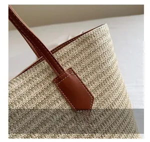 Close-up of hand-woven straw bag showing leather handle stitching and striped texture