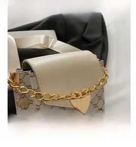Détail du sac à bandoulière beige avec motifs géométriques, chaîne dorée et breloque