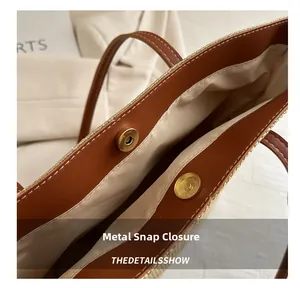Detail of golden magnetic snap closure on a woven tote bag with leather trim and fabric lining