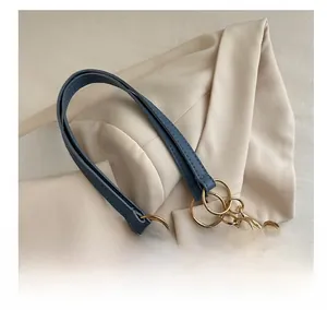 Close-up of blue denim tote bag with golden metal rings and leather handle details