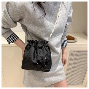 Detail of black drawstring bucket bag with floral texture and pearl chain strap
