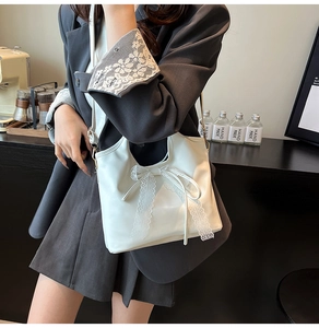 Primer plano del elegante lazo de encaje y la textura de cuero en el bolso de hombro blanco