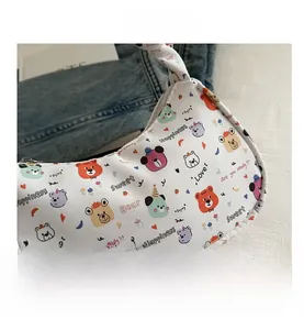 Close-up of white crescent canvas bag featuring colorful cartoon bear prints and letters