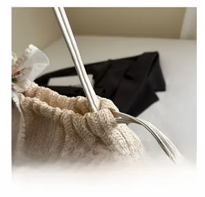 Detailaufnahme der cremefarbenen Stricktasche mit Wellenstruktur und zarter floraler Spitze