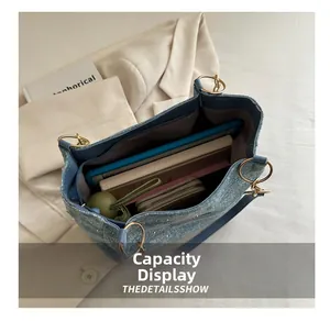 Detail view of denim tote bag capacity showing tablet, wallet, and daily essentials