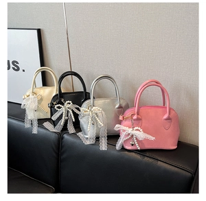 Detail view of mini bowling bags in cream, black, silver, and pink with lace bow charms