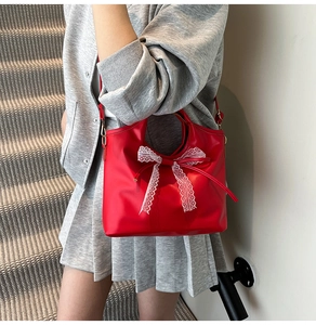 Detalle de bolso rojo en cuero de cera con lazo de encaje blanco grande y correa ajustable