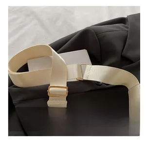 Détail de la bandoulière tissée crème avec boucle dorée et finitions en cuir
