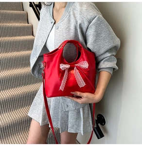Detalle del bolso rojo con lazo de encaje blanco y correa de hombro desmontable