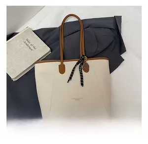 Detail of cream tote bag with brown straps and stylish plaid scarf accessory